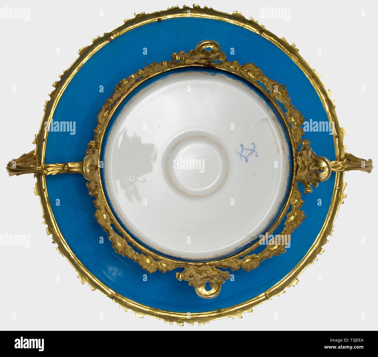 A large porcelain dish, Sèvres Factory, 19th century Sèvres-blue glazed porcelain with a hand-painted lovers' scene in the centre, the border has gilt and etched leafy vines and three cartouches with hand painted floral decoration. A reverse 'S' mark in underglaze blue on the bottom. Openwork support of gilt bronze with grape and grape leaf decoration on the four footed frame as well as floral garlands on the plate rim and the two handles. Diameter ca. 37 cm. Height ca. 20 cm. At the latest, porcelain from the French Sèvres Factory enjoyed great , Additional-Rights-Clearance-Info-Not-Available Stock Photo