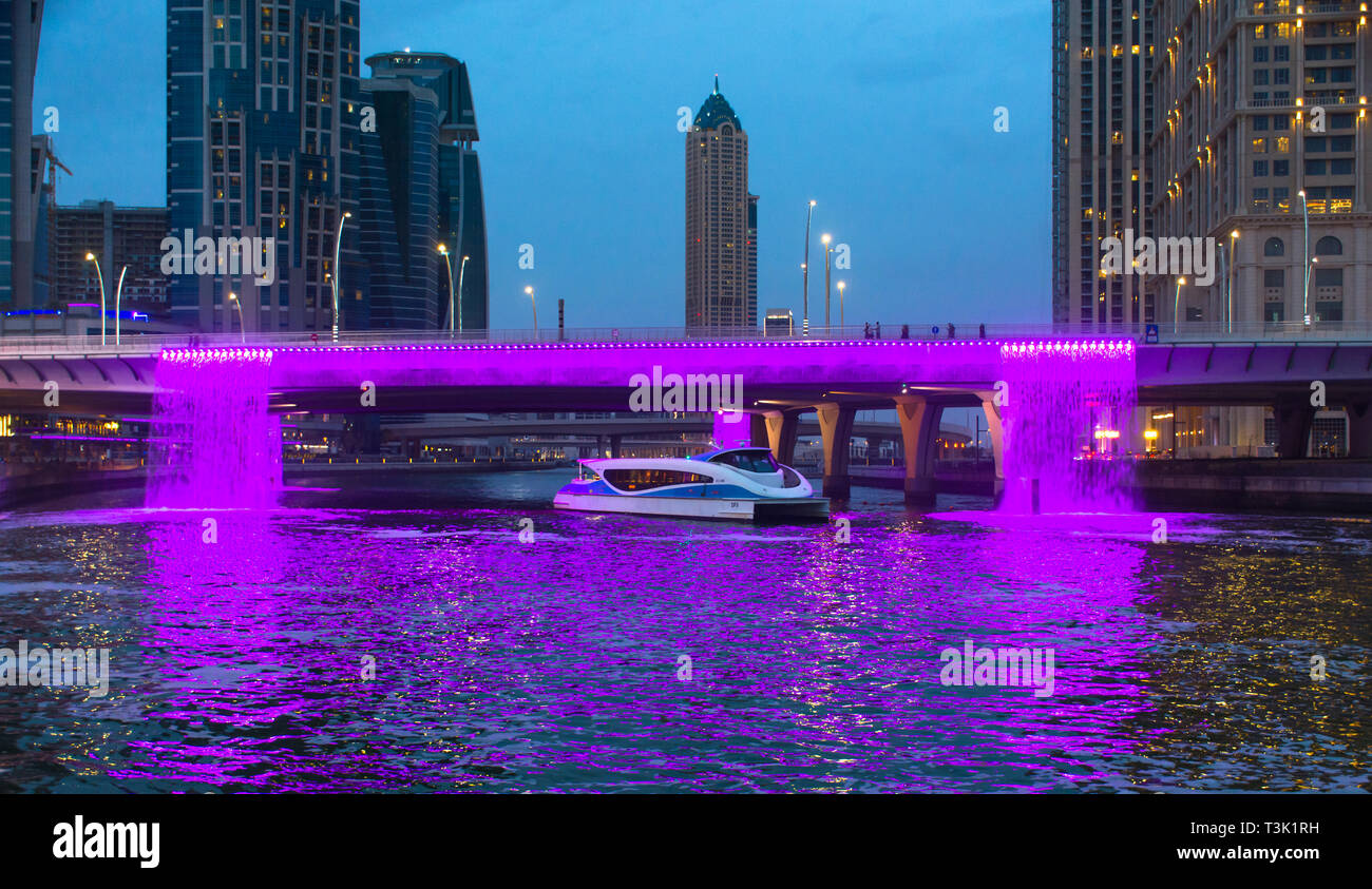 Water Canal Bridge Dubai Famous attraction of Middle UAE, RTA boat pass through colorful illuminated water fountain place to visit in Dubai Stock Photo