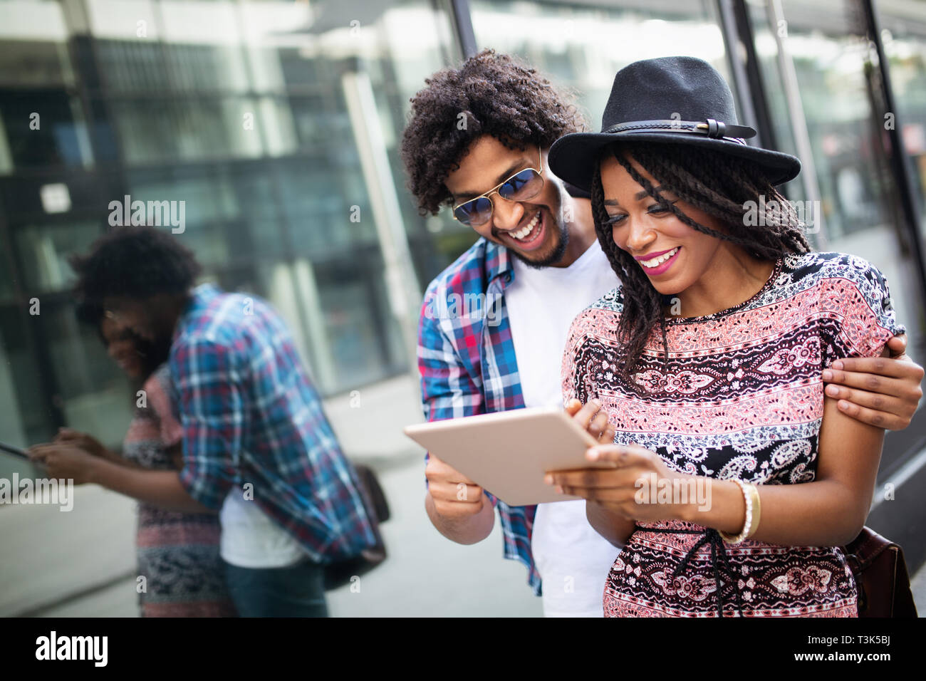 Attractive young african students are using a digital tablet and smiling while standing outside Stock Photo