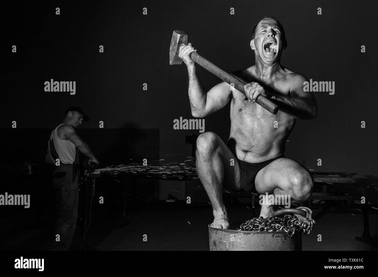 Screaming man with sledgehammer on an oil drum Stock Photo