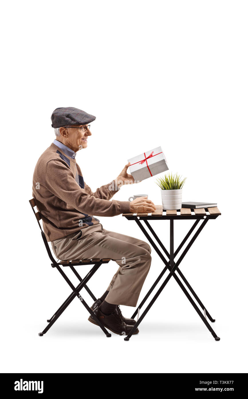 Full length profile shot of a senior man sitting at a cafe and holding a present isolated on white background Stock Photo