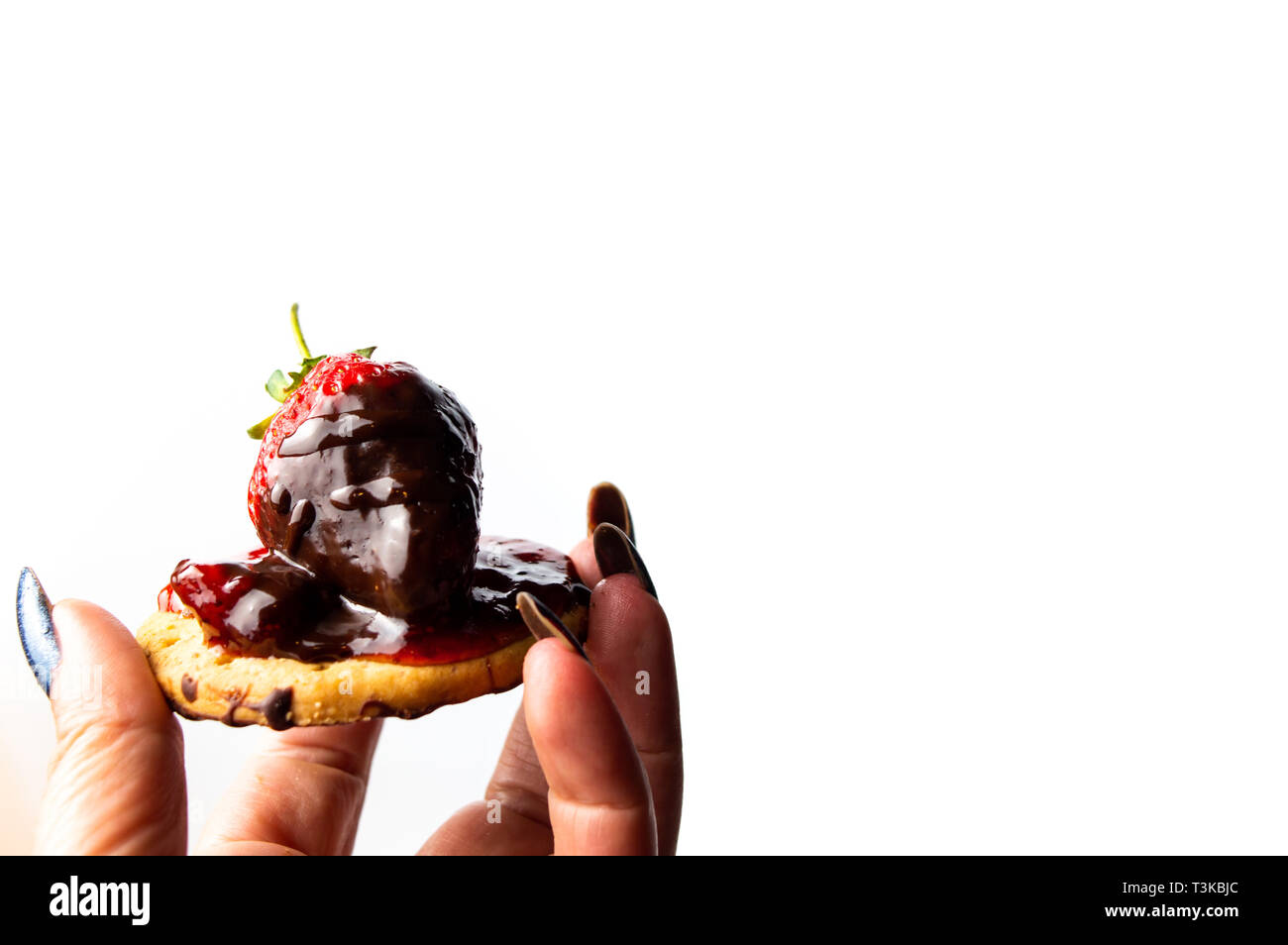 Hand holding strawberry dessert on a biscuit with jam Stock Photo