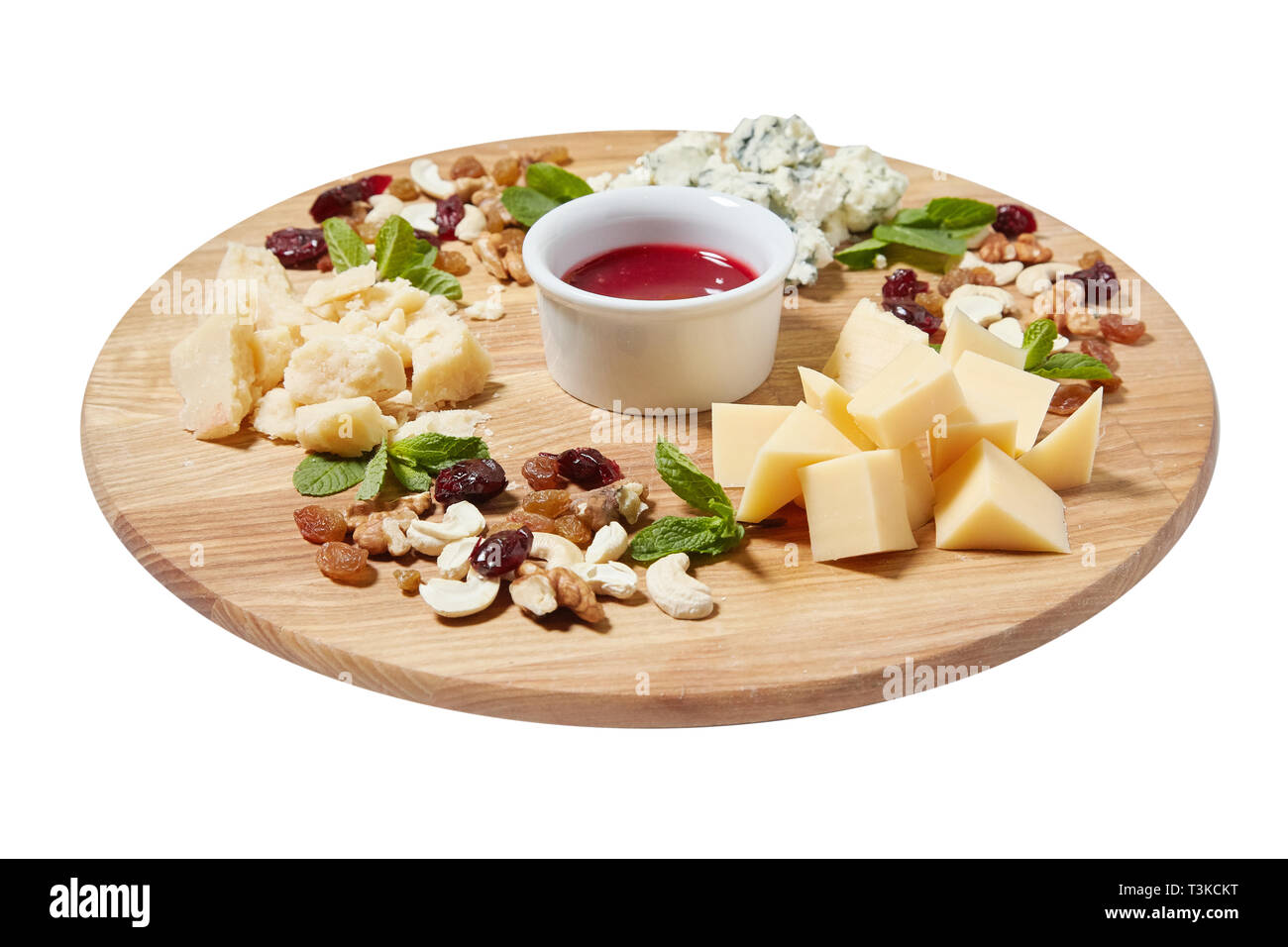 Cheese plate antipasti snack with mixed Italian cheese, cashew, fresh mint leaves, walnuts, raisins on wooden serving board on white background, Stock Photo