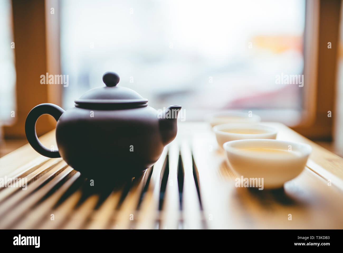 Teapot and cups with chinese tea near window on the table for the tea