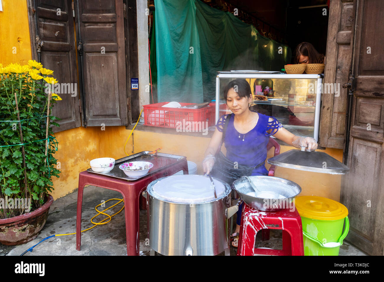 Vietnamese woman making rice paper cakes on a back street in the old