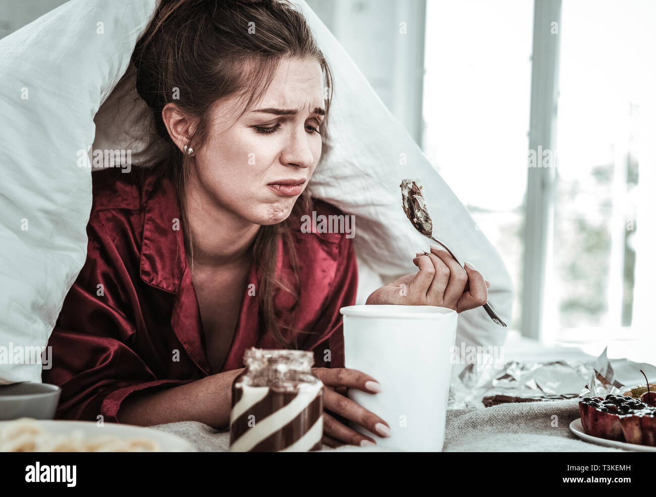 Depressed woman eating a lot of sweets Stock Photo Alamy