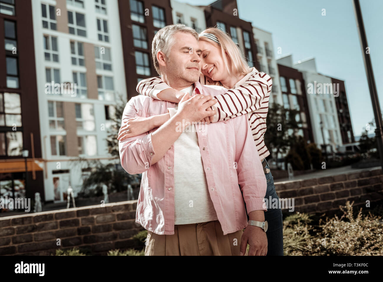 Positive blonde young woman hugging her husband Stock Photo - Alamy
