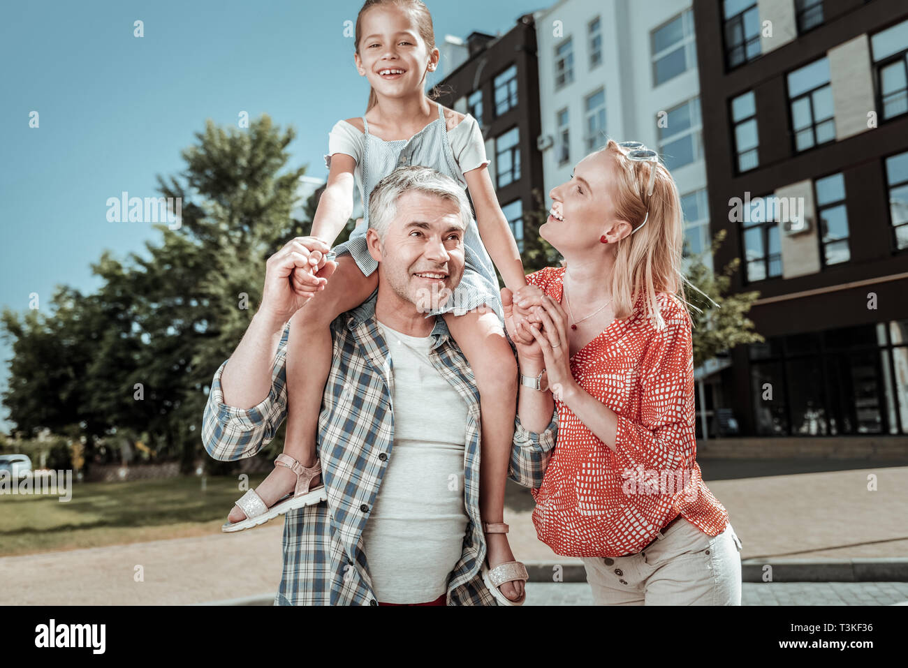 Nice happy girl sitting on her dads shoulders Stock Photo