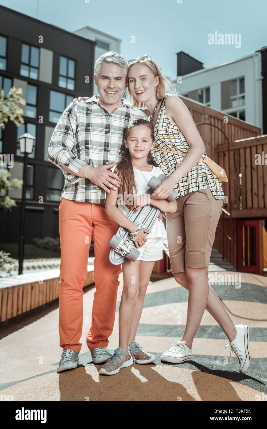 Positive happy parents standing with their daughter Stock Photo