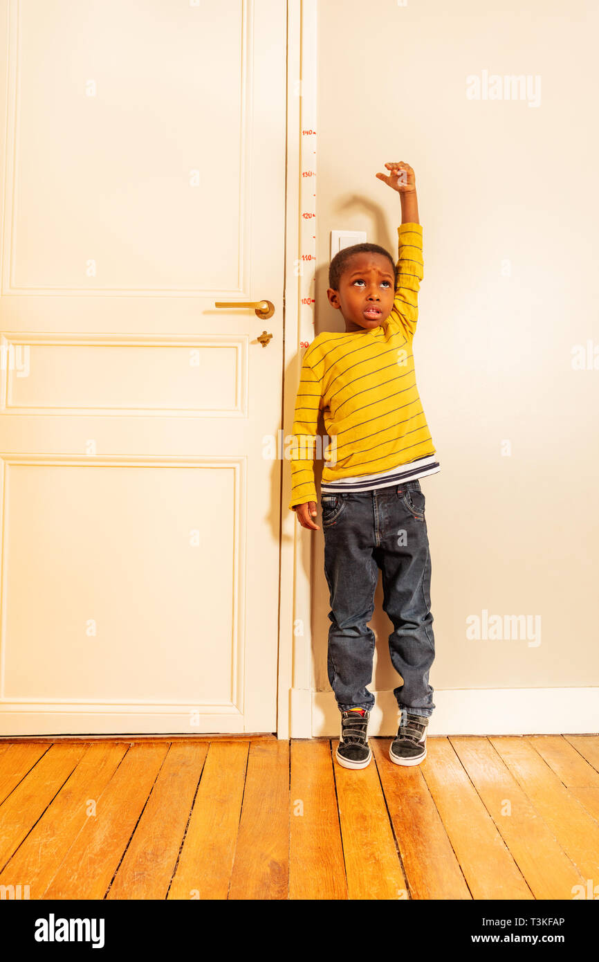 boy measuring his height benchmark on door at home Stock Photo