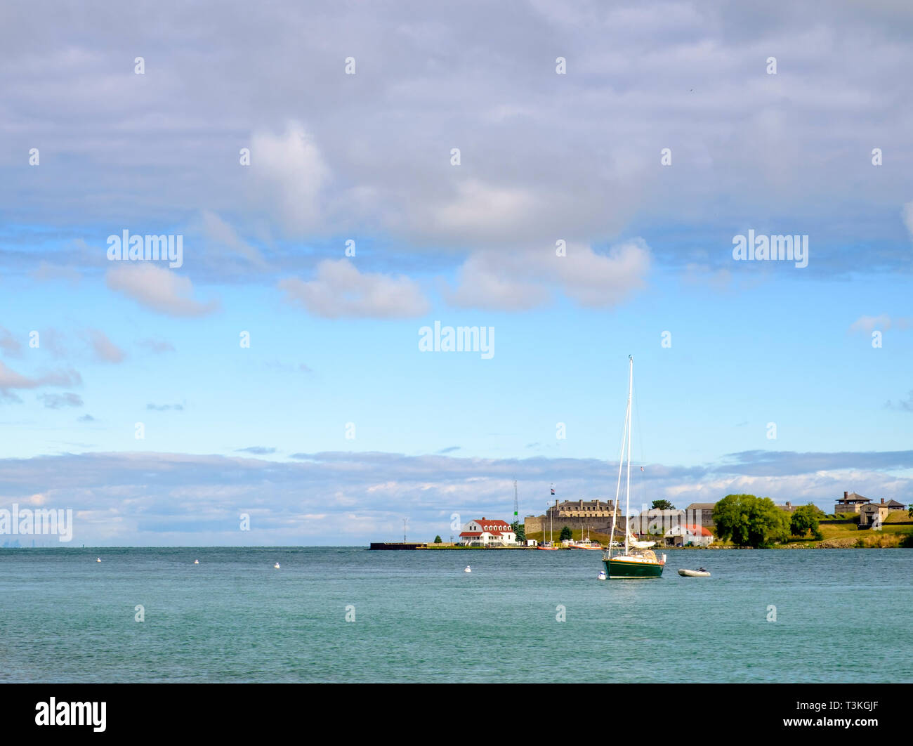 A sail boat moored on the Niagara River at the mouth of Lake Ontario. Fort Niagara in Youngstown New York is in the distance. Stock Photo