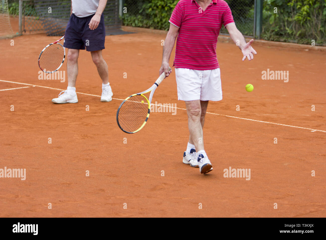 Doubles tennis player with partner in the background Stock Photo