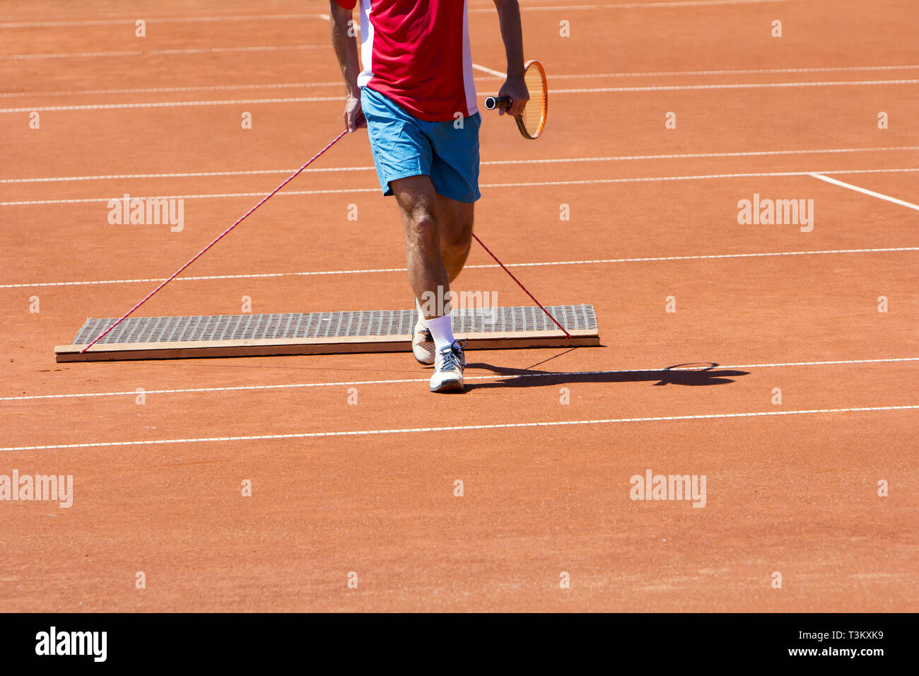 Player aligns surface tennis court, with pulling network Stock Photo