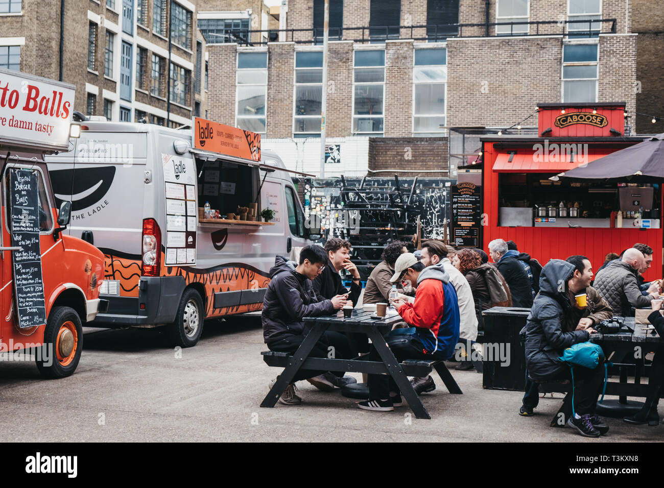 London, UK - April 6, 2019: People enjoying street food in Ely's Yard, a popular industrial-style street food market just off Brick Lane, East London. Stock Photo