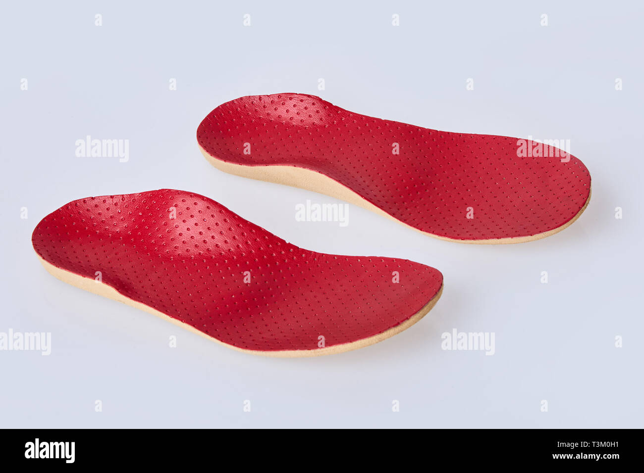 Orthotics on a white background. Insert in shoes to support the foot. Red leather medical insole