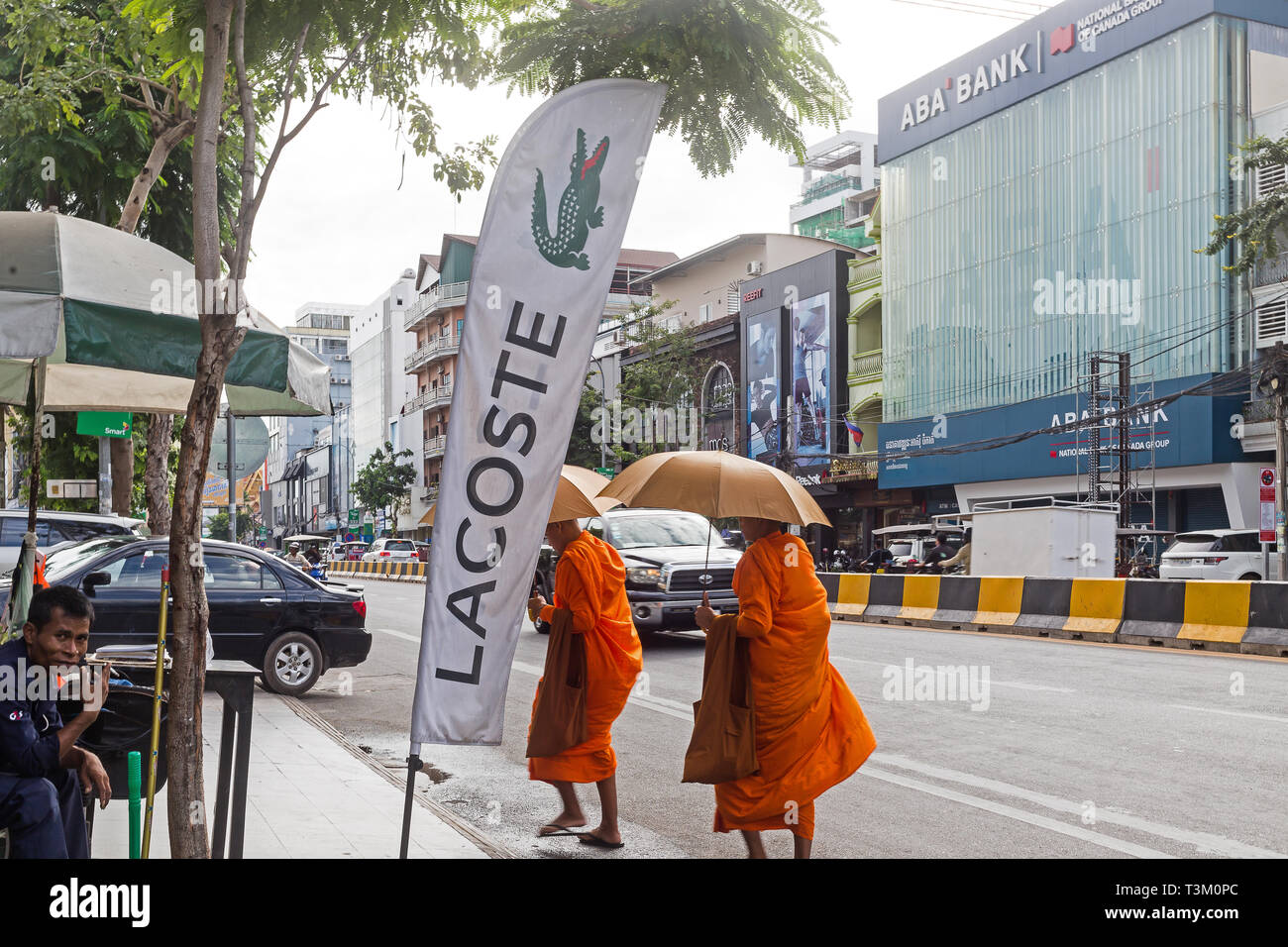 funny streets phnom penh captures with biddhist monks walking by the main road and banks and luxury brands Stock Photo