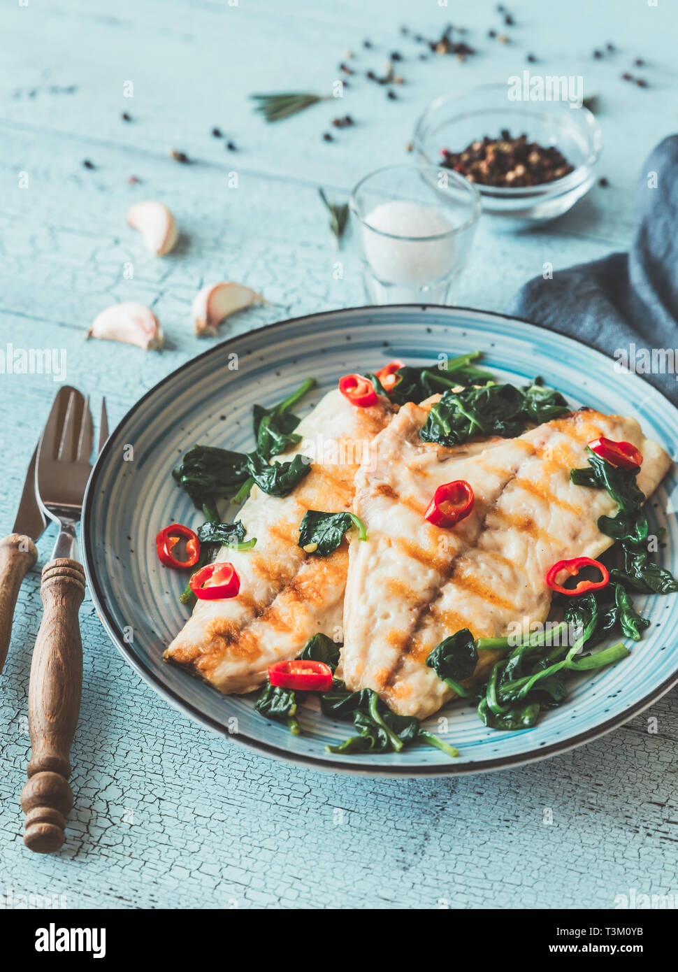 Grilled sea bream fish fillet with spinach and chili pepper Stock Photo