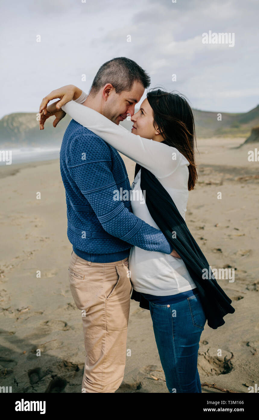 Pregnant woman hugging partner on the beach Stock Photo