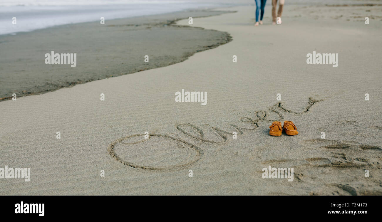 Baby name written in sand with shoes Stock Photo