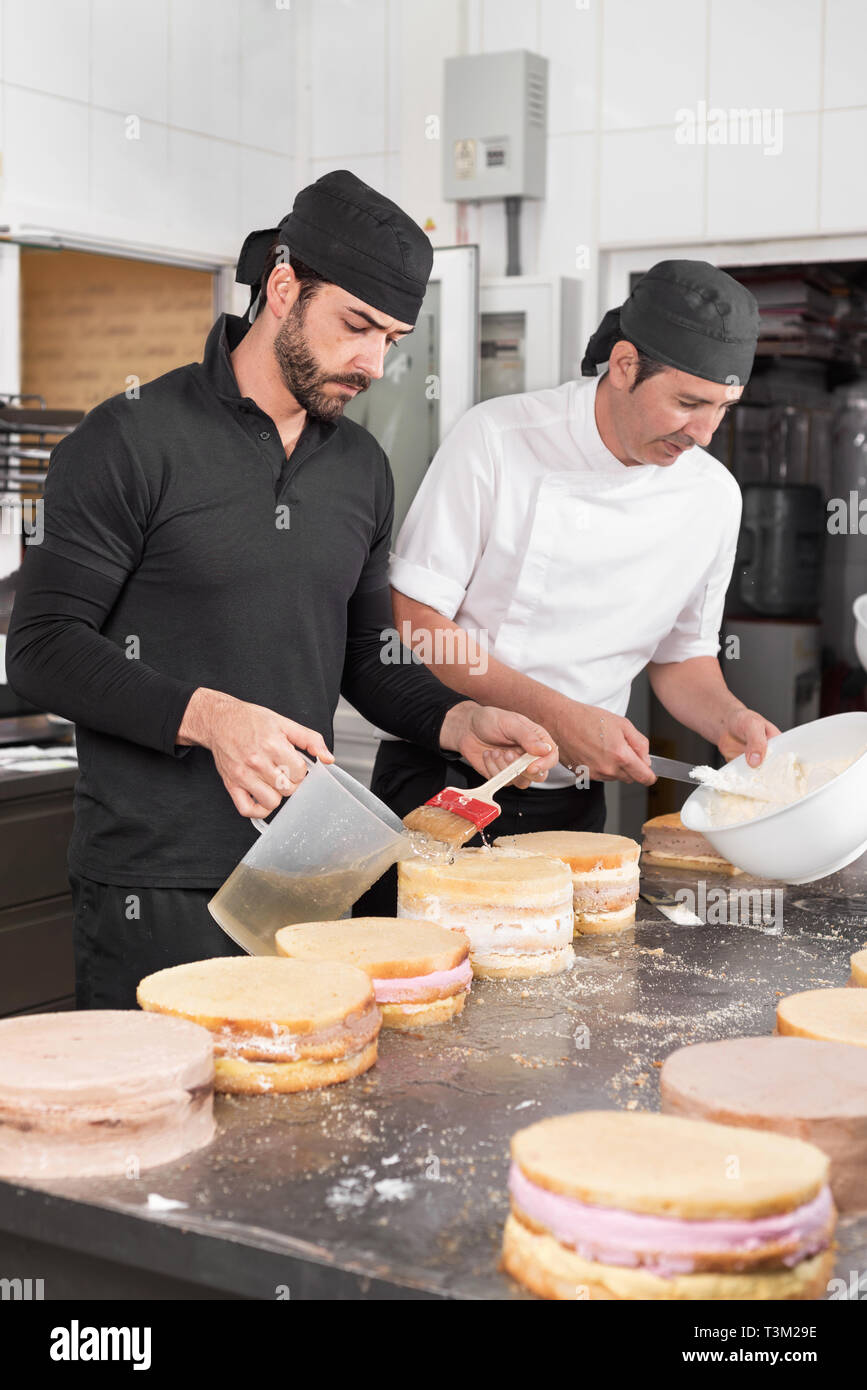 Two man pastry chefs working together making cakes at the pastry shop