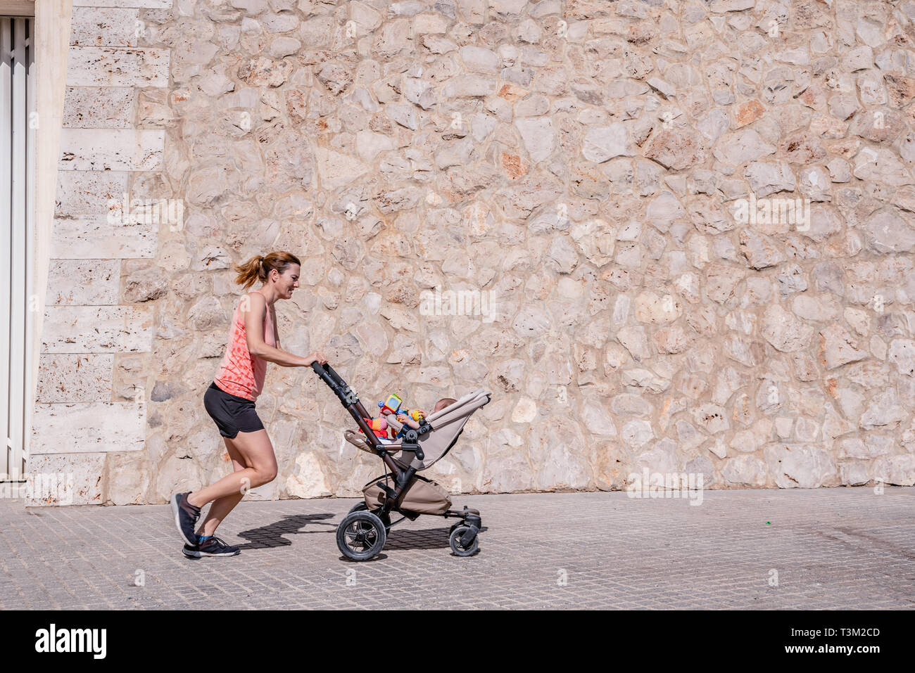 Running With Baby Young mother running with the stroller of her baby to stay in shape ...