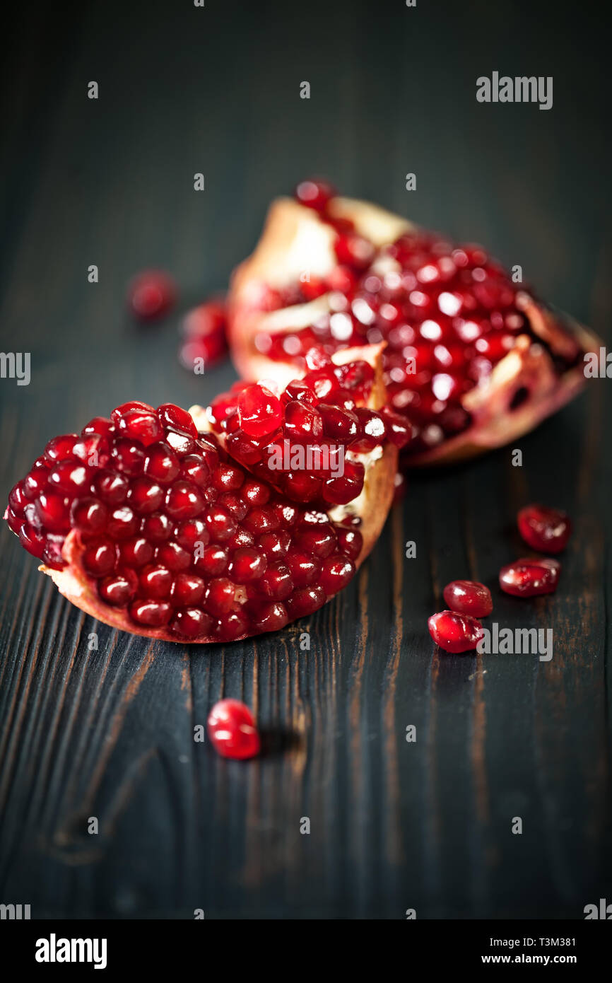 Ripe pomegranate fruit on a old black wooden vintage background. Background with copy space. Stock Photo