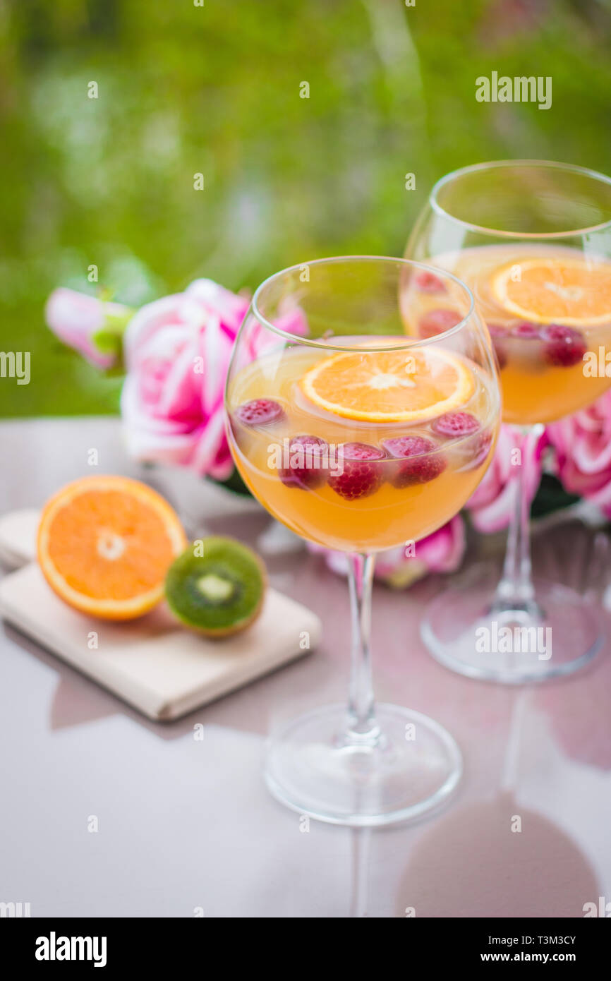 Orange vodka cocktail in elegant wine glass with kiwi, roses and