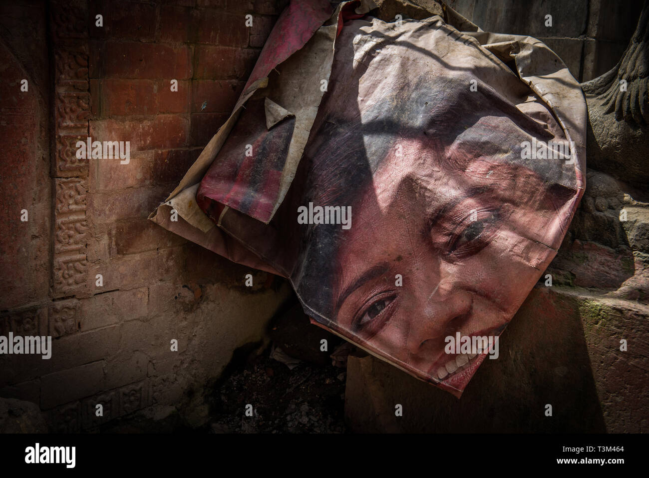 canvas with woman's face printed on it draped over a wall in bright sunlight, Kathmandu, Nepal Stock Photo