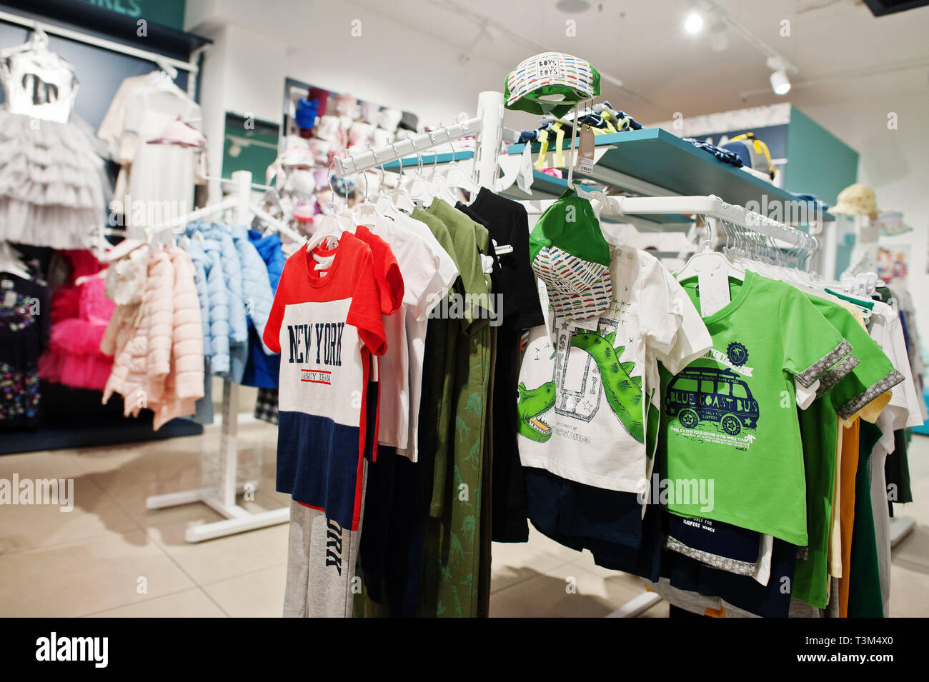Children's bright clothes hang on the display in the baby clothing store. Boys section. Stock Photo