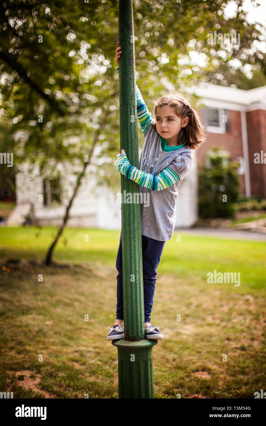 Young girl standing on pole outside her house. Stock Photo