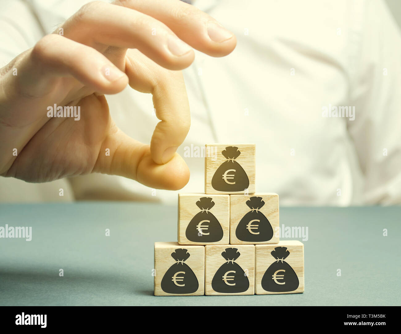 Businessman removes the cube with the image of the euro. Capital outflow. Pressure on small businesses. Bankruptcy. Economic recession. The concept of Stock Photo