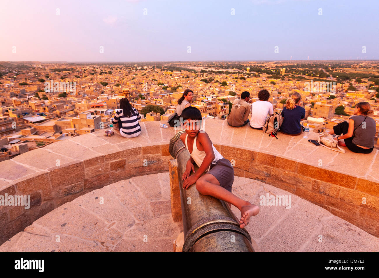 Local boy in Cannon at Jaisalmer Fort with tourists looking Jaisalmer city at sunset, Rajasthan, India Stock Photo