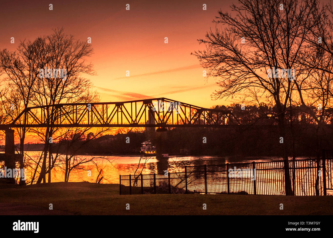 The sun sets on the M&O Railroad trestle, viewed from the Tuscaloosa Riverwalk, March 18, 2014, in Tuscaloosa, Alabama. Stock Photo