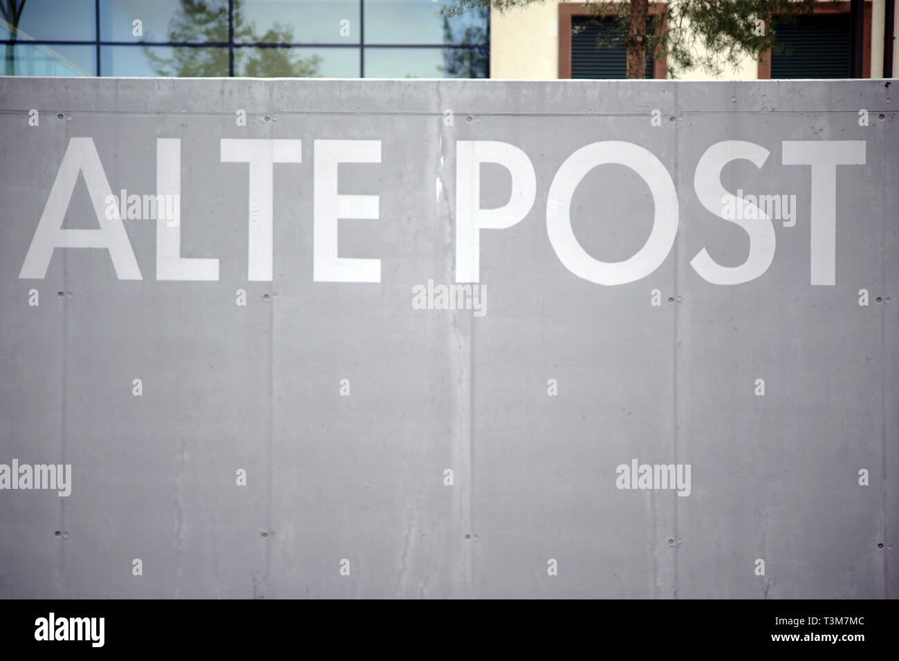 The inscription 'Alte Post' in English Old Post office, on the gray wall of a parking lot border in Pirmansens. Stock Photo