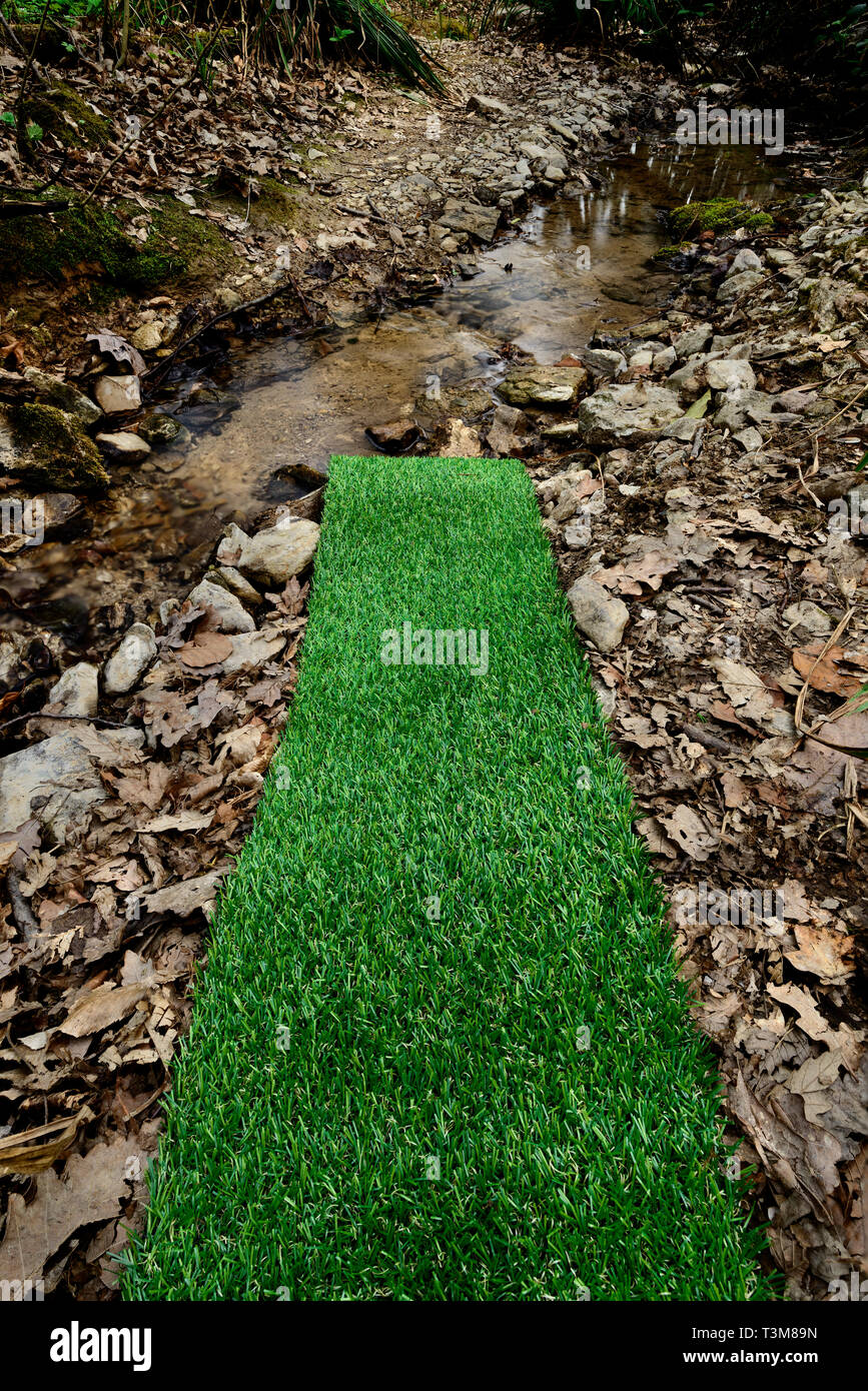 Artificial green plastic grass carpet by the river Stock Photo