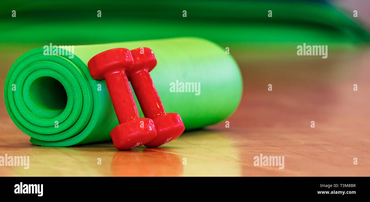 green sports mat for physical activities and dumbbells on the floor Stock Photo