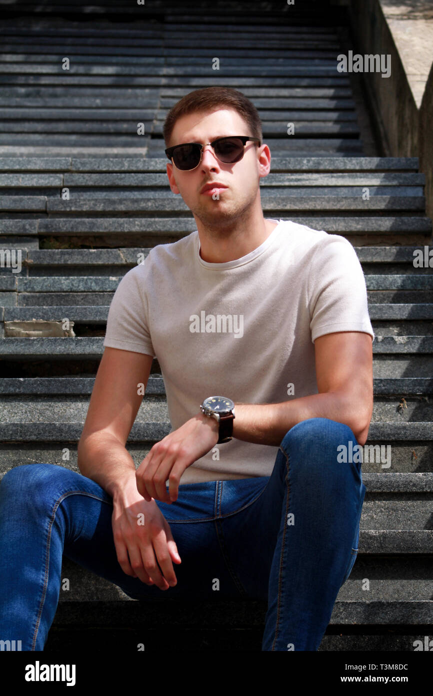 Man sitting alone on steps. Handsome boy with sunglasses. Male model ...