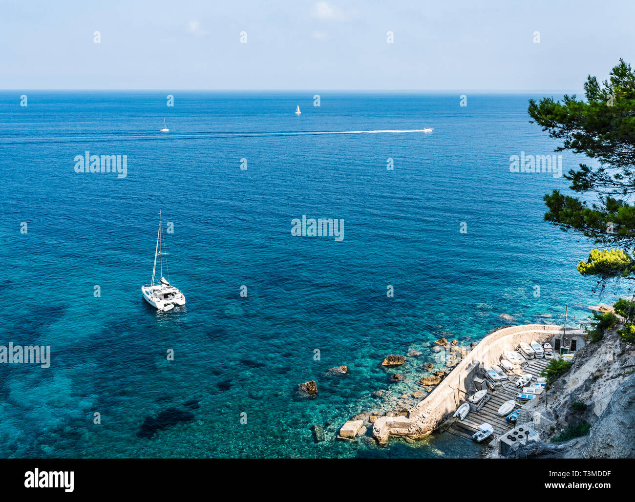 beautiful turquoise mediterranean sea with small harbor and sailboat on sunny day Stock Photo