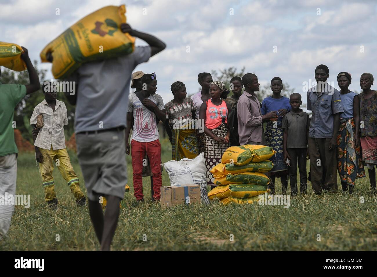 Local volunteers assist in unloading food aid from a helicopter in the aftermath of the massive Cyclone Idai April 8, 2019 near Bebedo, Mozambique. The World Food Programme, with help from the U.S. Air Force is transporting emergency relief supplies to assist the devastated region. Stock Photo