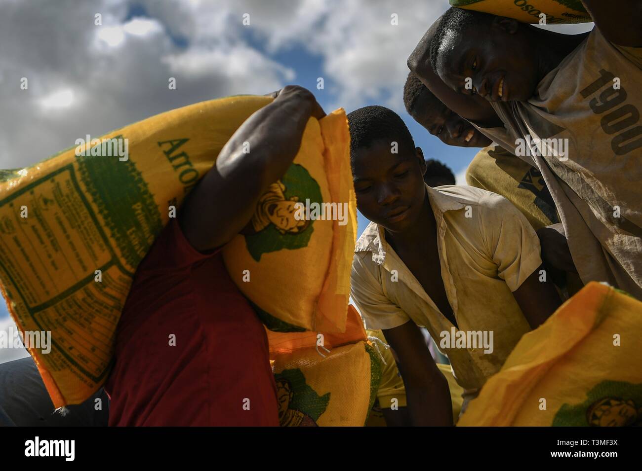 Local volunteers assist in unloading food aid from a helicopter in the aftermath of the massive Cyclone Idai April 8, 2019 near Bebedo, Mozambique. The World Food Programme, with help from the U.S. Air Force is transporting emergency relief supplies to assist the devastated region. Stock Photo