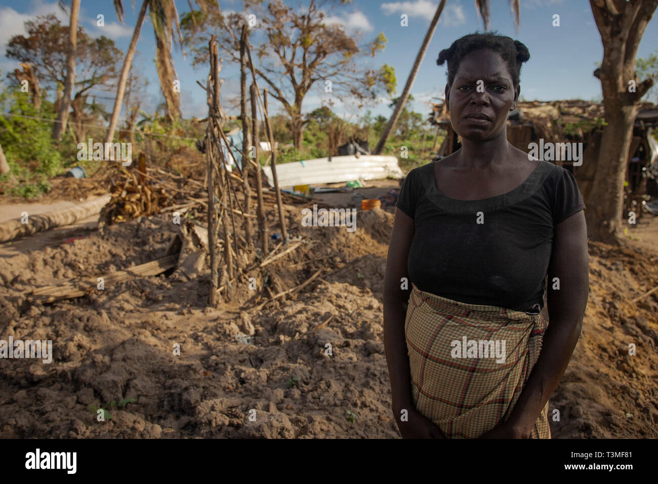 A Mozambican woman stands in front of the remains of her home in the aftermath of the massive Cyclone Idai April 6, 2019 in Nhagau, Mozambique. The World Food Programme, with help from the U.S. Air Force is transporting emergency relief supplies to assist the devastated region. Stock Photo