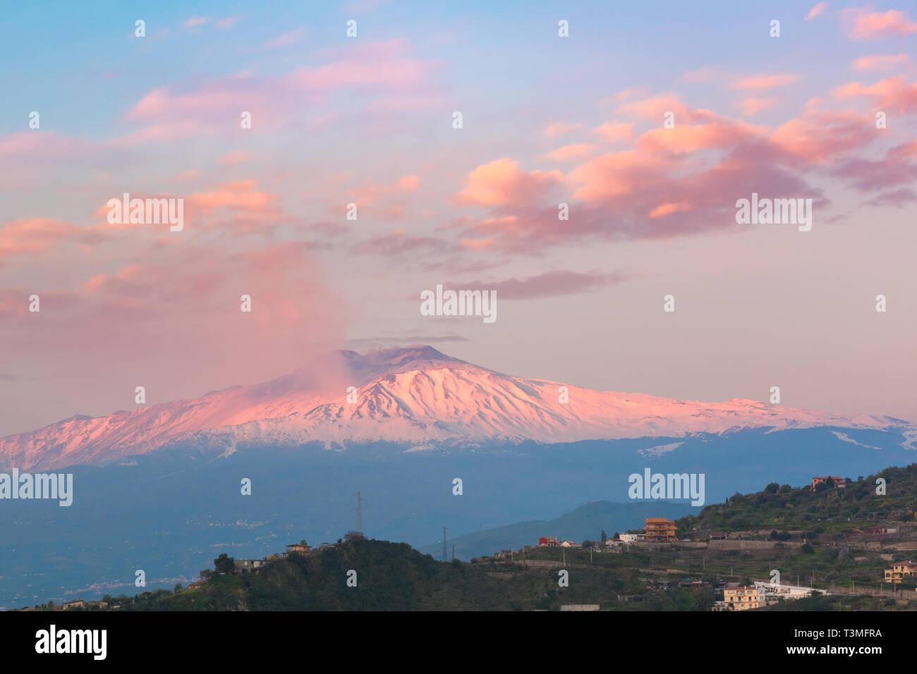 Smoking snow-capped Mount Etna volcano at sunrise, as seen from Taormina, Sicily Stock Photo