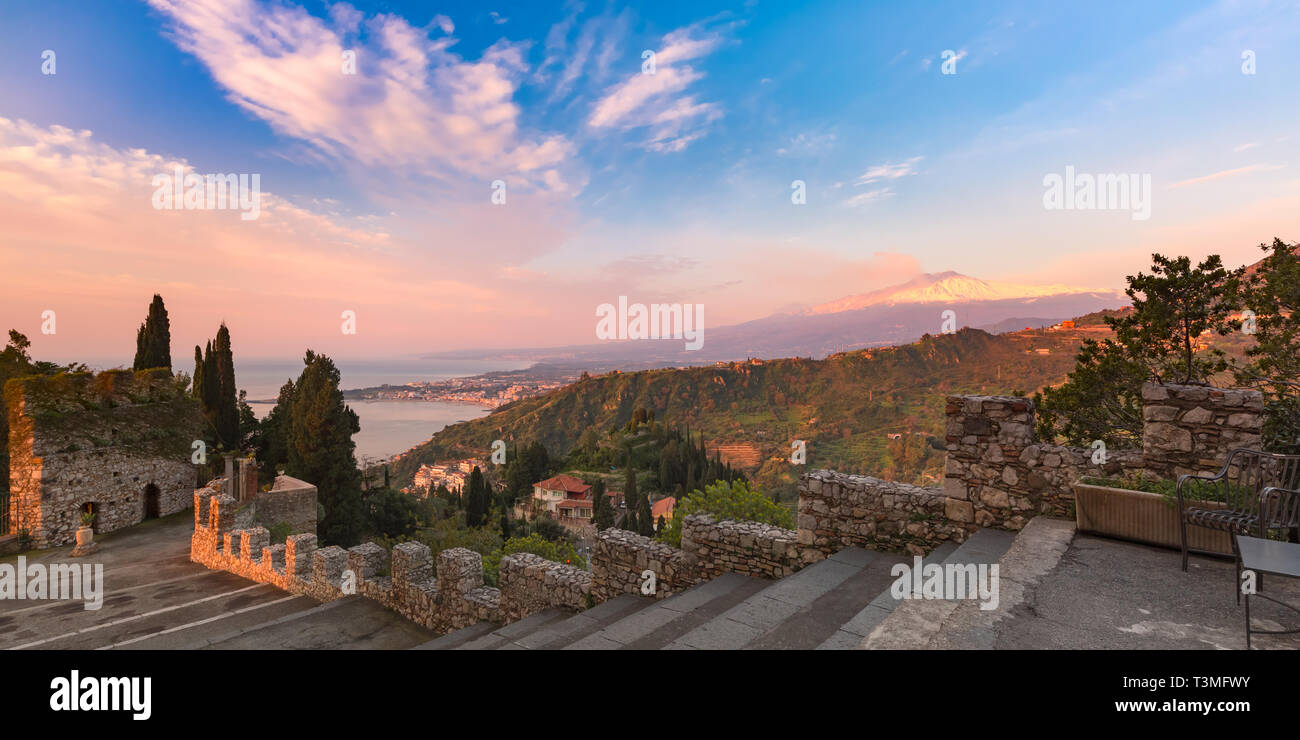 Panoramic view of smoking snow-capped Mount Etna volcano at sunrise, as seen from Taormina, Sicily Stock Photo