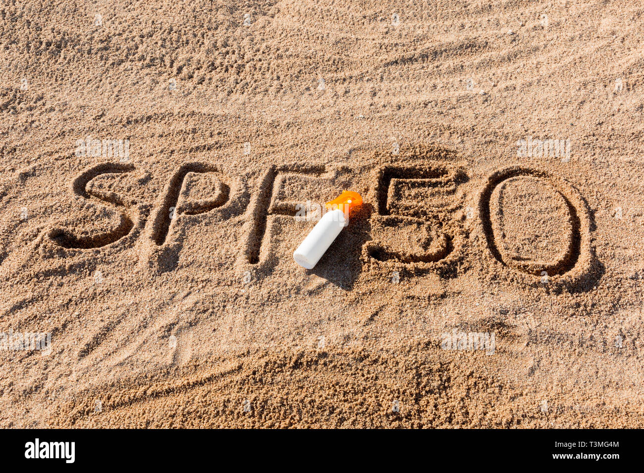 Sun protect factor fifty. SPF 50 word written on the sand and white ...