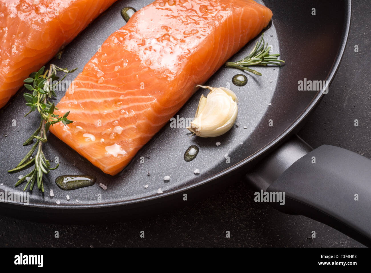 Salmon Steaks Fresh and Raw in Frying Pan with Thyme and Garlic Stock Photo