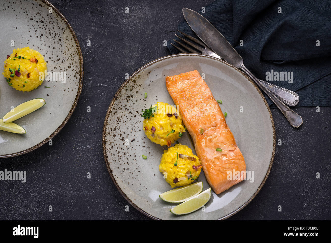 Grilled Salmon Fillet with Saffron Risotto on Dark Background Stock Photo