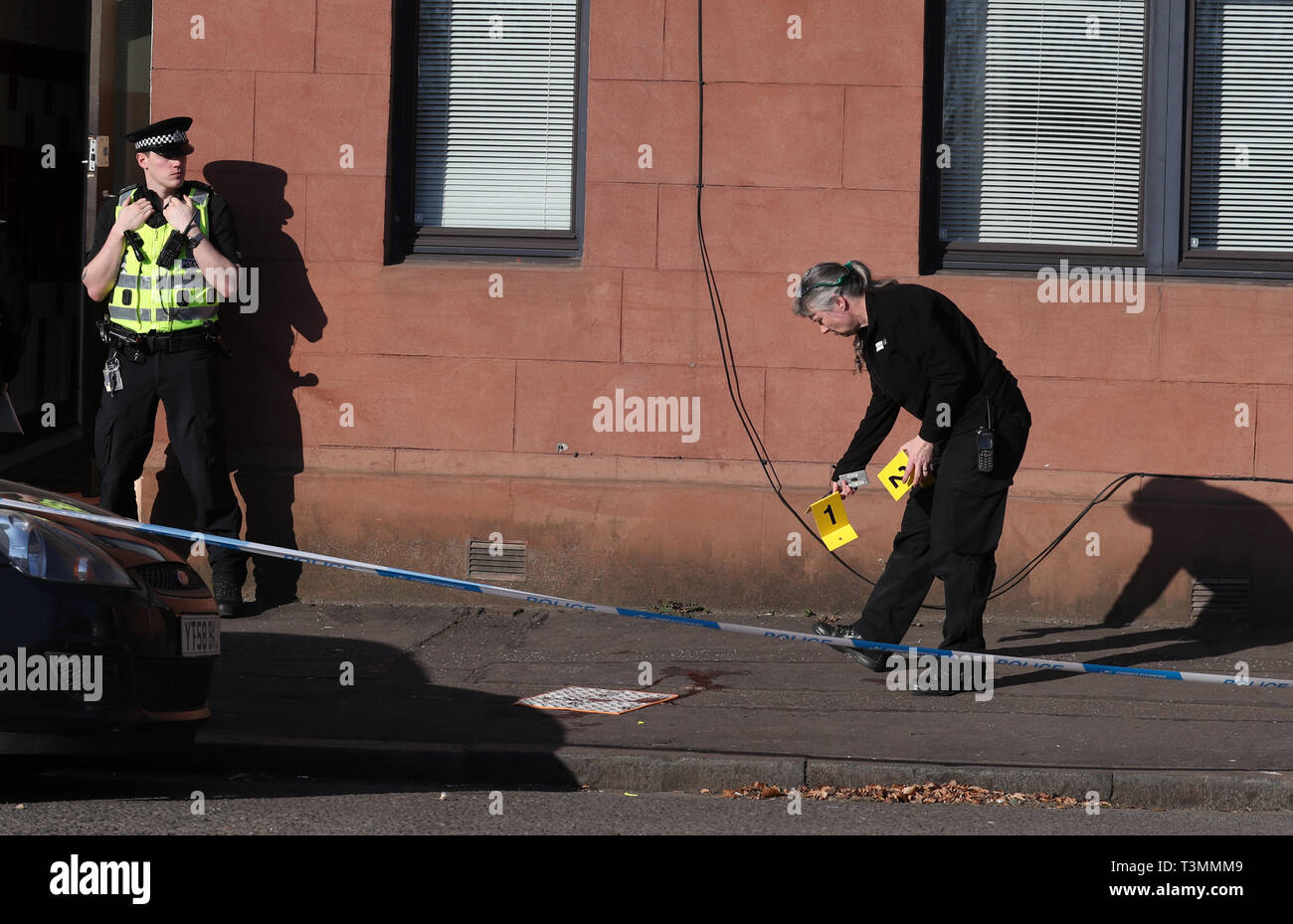 Police mark out a blood stain outside a block of flats on Dumbarton Road, close to Boquhanran Road, in Clydebank, West Dunbartonshire where a two-year-old girl is in hospital after falling from a window. Stock Photo