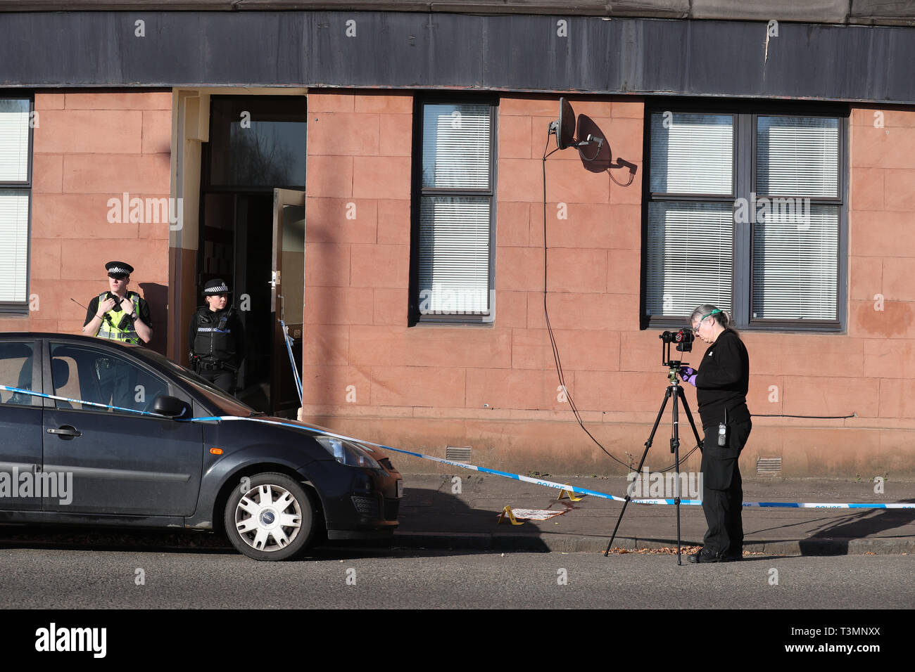Police mark out a blood stain outside a block of flats on Dumbarton Road, close to Boquhanran Road, in Clydebank, West Dunbartonshire where a two-year-old girl is in hospital after falling from a window. Stock Photo