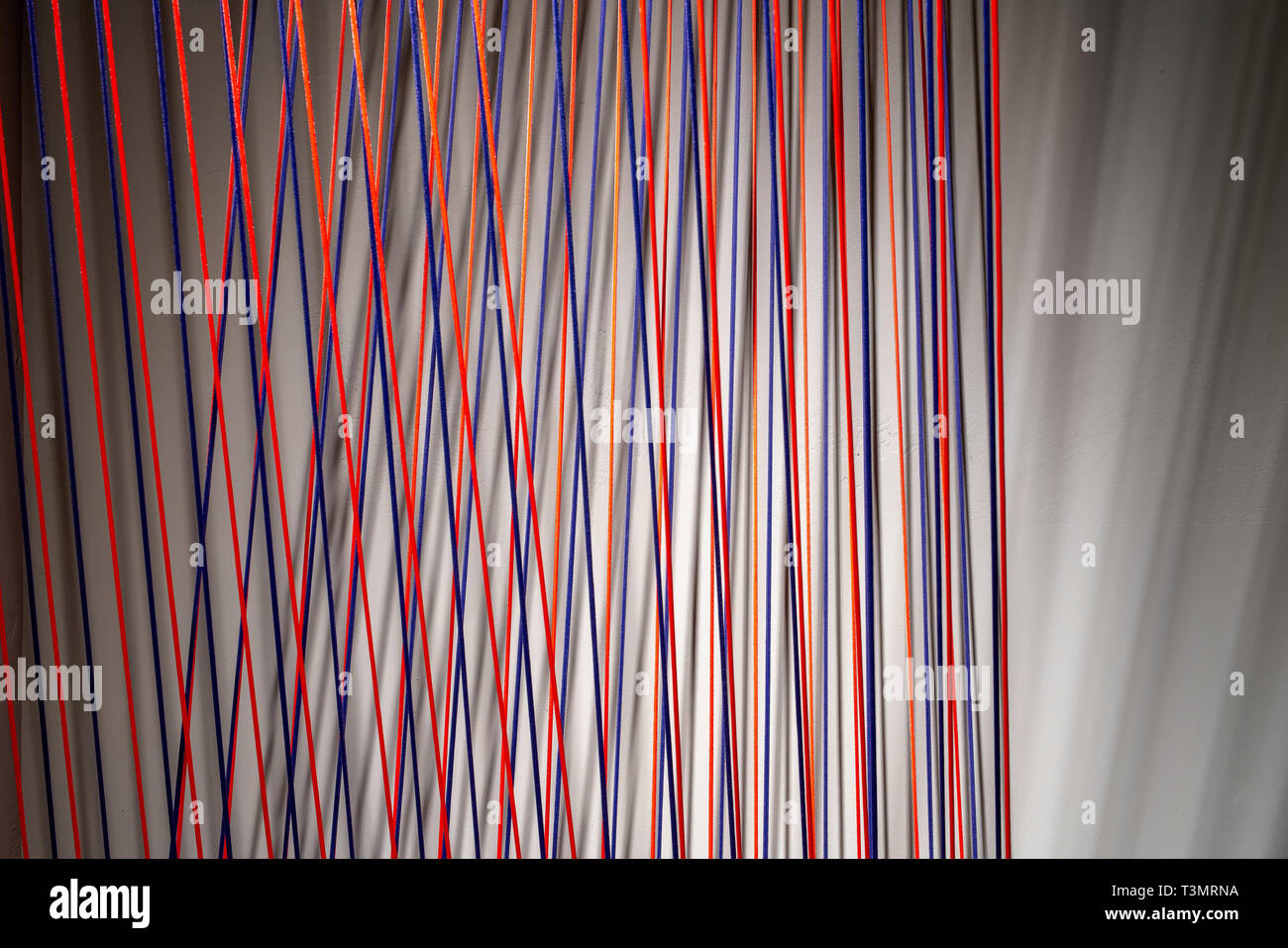 Multicolored ropes lines installation in illuminated interior Stock Photo