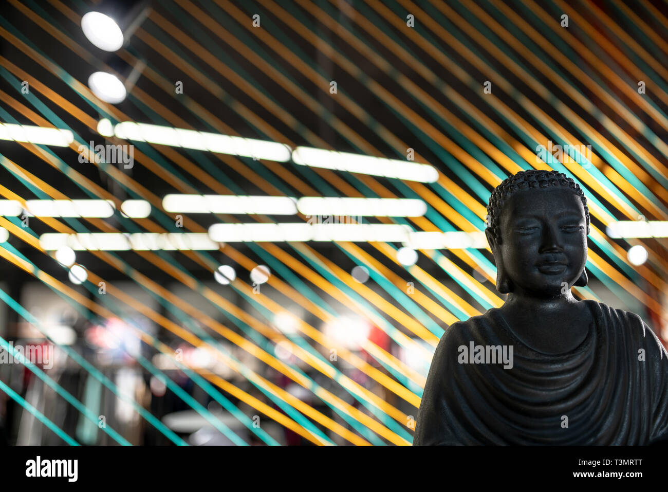 Bust of Buddha in illuminated interior with colorful ropes lines installation Stock Photo